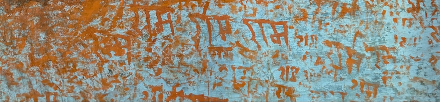 Orange Graffiti of word Ram in Devanagari writing on light blue wall